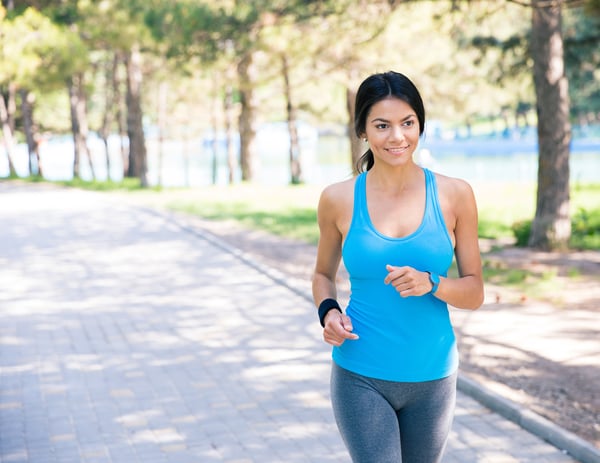 Smiling sporty woman running outdoors in park