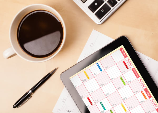 Workplace with tablet pc showing calendar and a cup of coffee on a wooden work table close-up-1